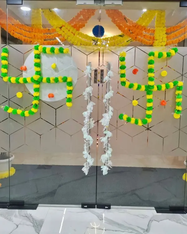 A traditional Swastika symbol made from marigold flowers on the main glass door, creating an auspicious and welcoming entrance for Diwali.