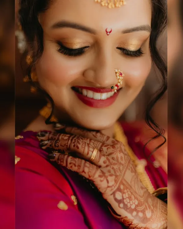 This is the look I live for: fresh, dewy, and absolutely radiant. My goal is to create makeup that feels like a second skin, letting your natural beauty shine through on your most special day. This classic Marathi bridal look features soft golden eyes and a bold red lip.