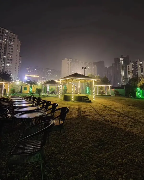 Our venue transforms at night into a magical space. This wide view shows our expansive lawn with glowing gazebos and fairy lights, offering a unique open-air party venue against the city skyline.
