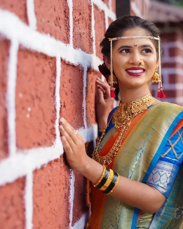 I love using different textures and backgrounds for bridal portraits. Here, the rustic red brick wall creates a beautiful contrast with the bride's elegant blue and orange saree and traditional gold jewellery, making the colors pop.