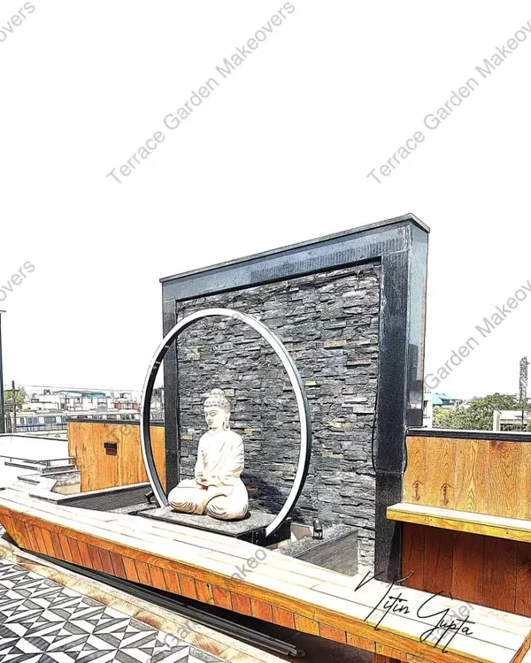 This is a perfect example of a modern Zen garden I created on a rooftop terrace. The design centers around a meditating Buddha statue within a circular light, a gentle water feature, a dark slate wall, and a built-in wooden bench for quiet contemplation.