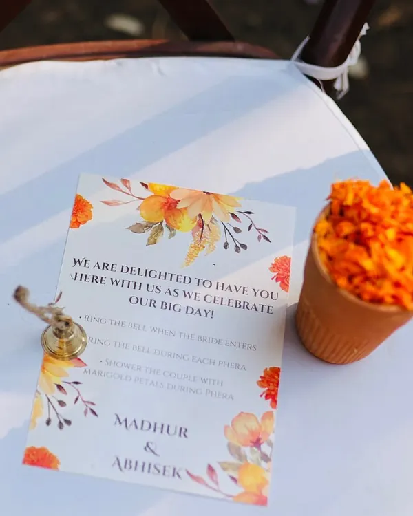A small detail that makes a big impact. For this temple style wedding, each guest's seat had a program card, a small bell to ring during the pheras, and a cup of marigold petals to shower the couple with blessings.