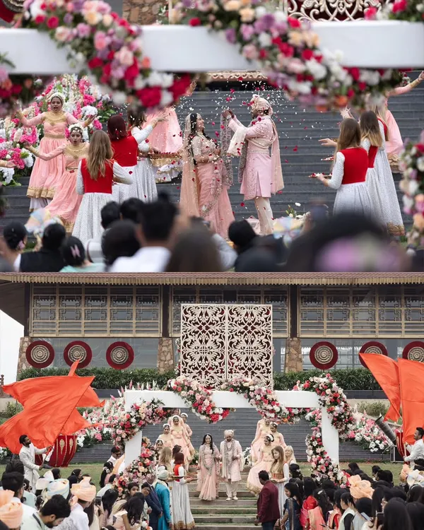 A grand view of Anisha and Rishabh's wedding ceremony, with dancers and guests creating a vibrant and festive atmosphere. This shot captures the scale and theatricality of a large Indian wedding.