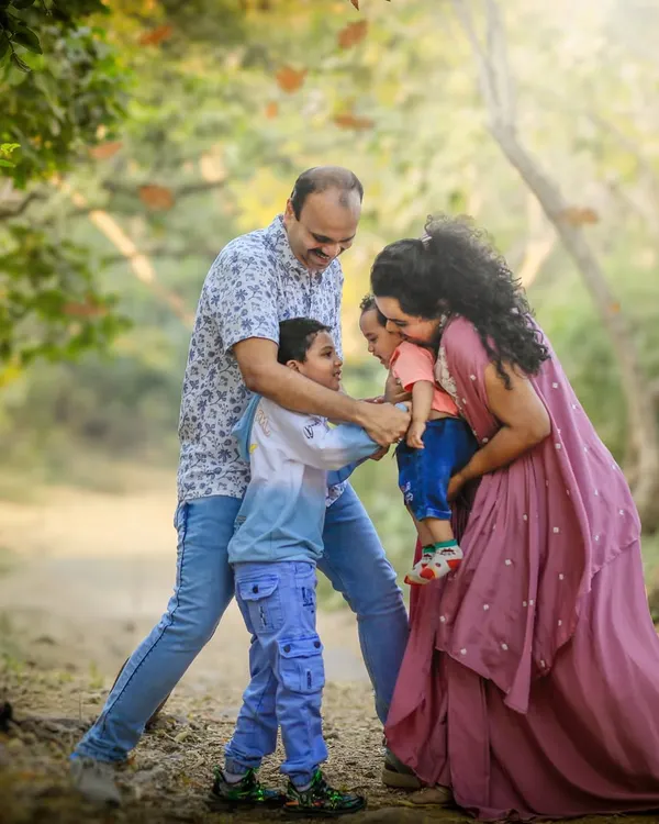 A family of four is captured in a moment of pure, chaotic joy on a rustic path, surrounded by trees. This image perfectly represents the lively and unposed nature of my outdoor family photoshoots.