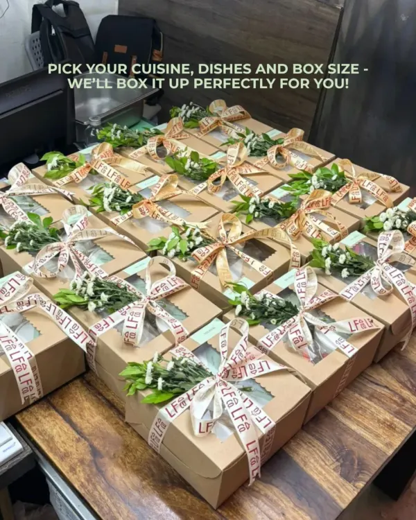 I can create beautifully customized boxes for any occasion. This image shows a large order of party boxes, each tied with a ribbon and a sprig of fresh flowers, ready for a special celebration. You pick the cuisine, dishes, and box size, and I'll handle the rest.