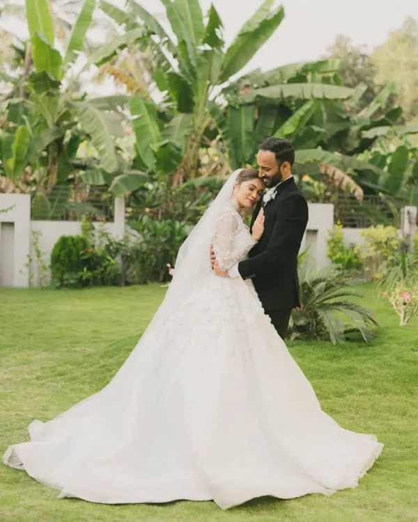 A quiet moment of connection in a lush garden setting. The bride's magnificent gown and the groom's classic suit create a timeless portrait of love and elegance.