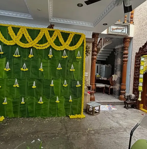 For an intimate home ceremony, we created this backdrop entirely from fresh banana leaves. The wall is decorated with small pendants made of jasmine and marigold flowers, creating a completely natural and traditional look.