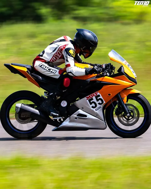 A side profile view of a rider executing a turn, demonstrating the correct tucked-in body posture to minimize drag and maintain stability at speed. This is a fundamental aspect of our motorcycle race training.