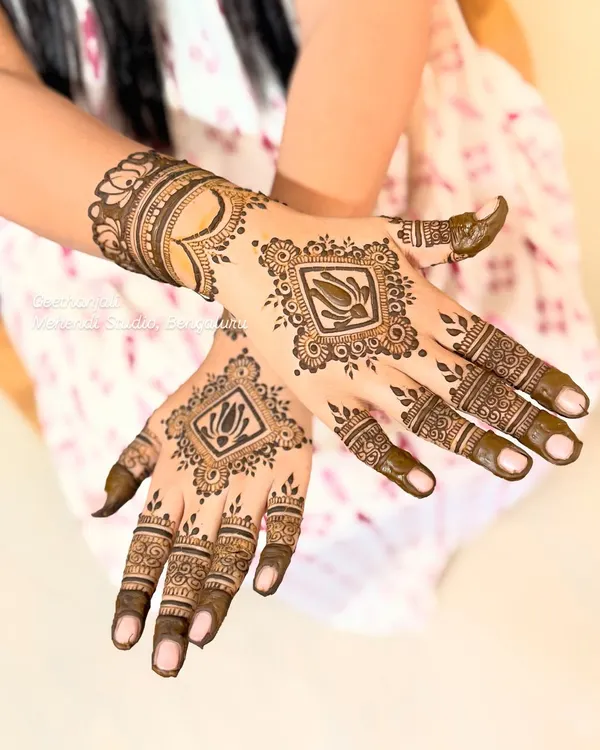 A modern and chic semi-bridal design. This look features a central framed lotus on the back of the hand, with detailed finger work and a heart motif on the wrist.
