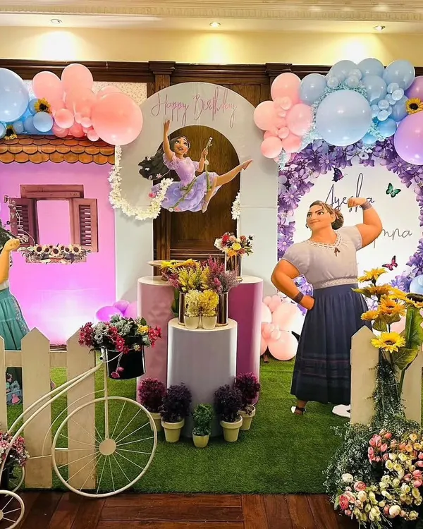 A vibrant and magical Encanto themed birthday party, featuring a full stage setup with character cutouts, a colorful balloon arrangement, and floral details that bring the movie to life.