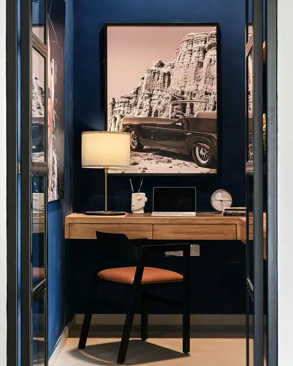 This small nook was transformed into a moody and functional home office. I added see-through glass and black metal doors for privacy without closing off the space. The deep blue walls and oversized artwork create a cool, inspiring backdrop for video calls.