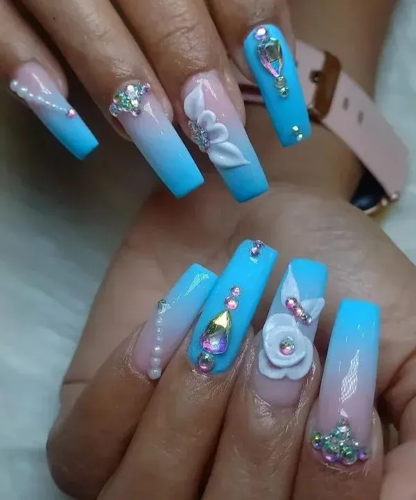 An extravagant display of 3D artistry on long, coffin-shaped extensions. This set features a blue ombré base, adorned with hand-sculpted white flowers, pearls, and a variety of iridescent rhinestones for a truly show-stopping look.