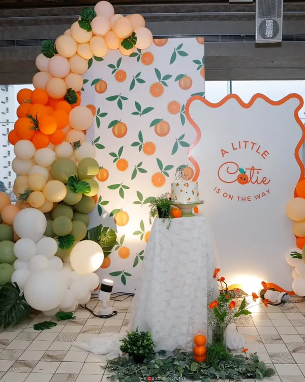 "A Little Cutie is on the way!" This vibrant backdrop, featuring a custom arch, orange-print wallpaper, and a cascade of citrus-toned balloons, was the cheerful centerpiece for a modern baby shower.