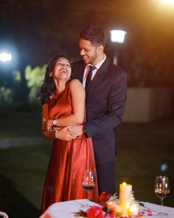 A romantic pre-wedding portrait session at night. The candlelight and warm lighting create an intimate and cozy atmosphere for this candid, laughing moment.