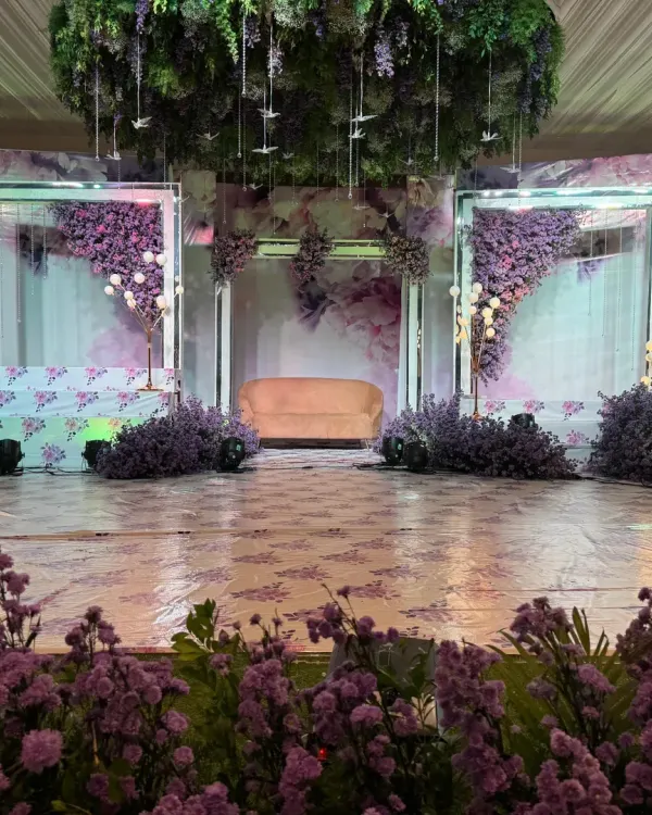 This reception stage is a dream in lavender. The design features a soft, romantic color palette, hanging floral installations, and modern lighting to create a whimsical and elegant atmosphere.