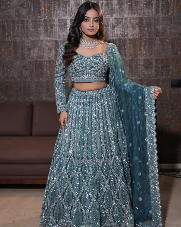 Emerald magic. This look strikes the perfect balance between softness and a statement, with shimmery lids and a bold green winged liner for the modern bride. The full view shows how it complements the stunning sequined lehenga.