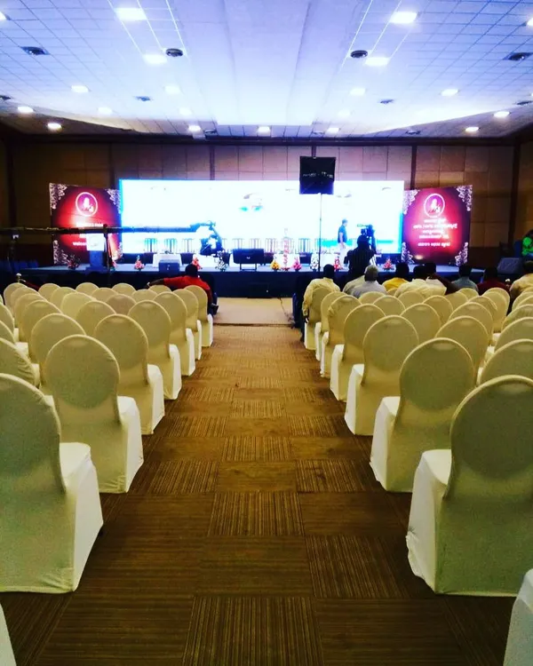 This is a view from the back of a conference hall before the event begins, showcasing a clean and organized seating arrangement. I ensure every detail is in place, from chair covers to the main stage setup, for a professional look.