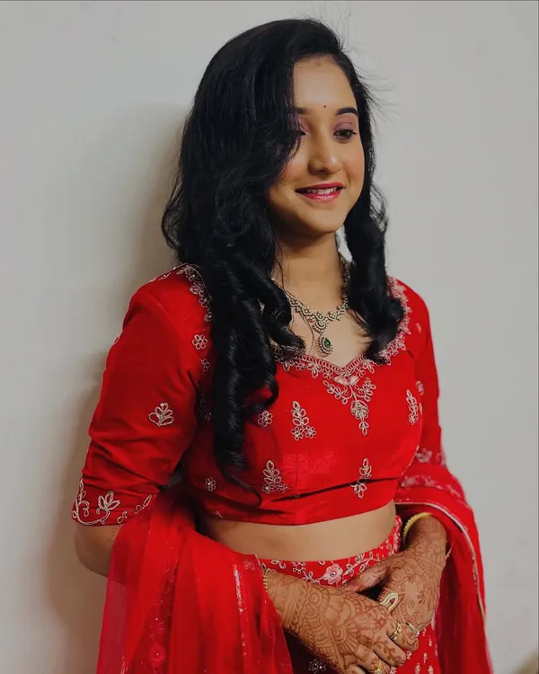 A happy client showing off her finished reception look. The soft curls frame her face beautifully, and the makeup is rosy and radiant, perfect for an evening party.