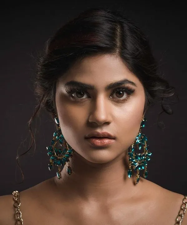 A captivating studio headshot for a model's portfolio. The clean, dark background and professional lighting put the full focus on her direct gaze and the elegant statement earrings.