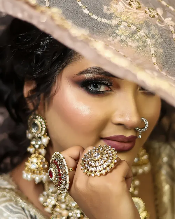 A perfect example of a modern bridal look, featuring a soft smokey eye, matte lips, and statement kundan jewelry. This close-up highlights the flawless base and intricate details we teach.
