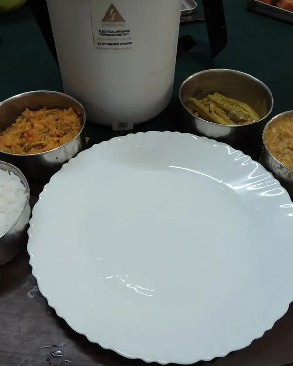 This is my homestyle vegetarian lunch parcel, prepared with less oil and balanced spices, just like a mother would make. It includes steamed rice, dal, a vegetable curry, and a side dish, all packed fresh for you.