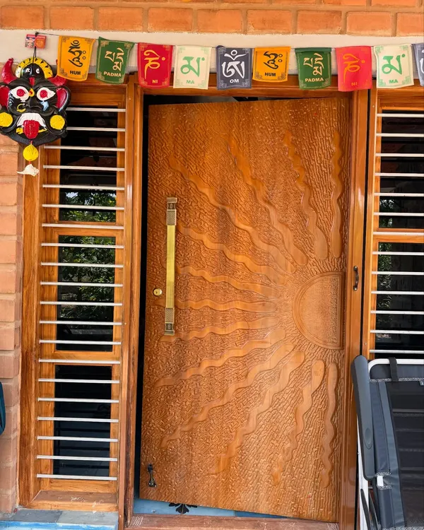 The main door is the first welcome to your home. For this farmhouse, we designed a custom teak wood door with a beautiful hand-carved sun motif, making a memorable first impression.