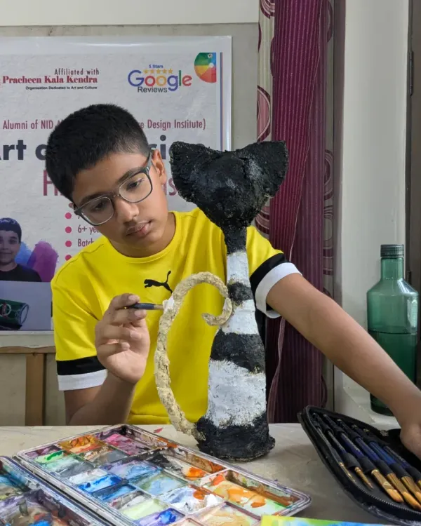 From paper and glue to a work of art. This student is adding the finishing touches to his creative papermache cat sculpture, learning about form, texture, and painting on a 3D surface.