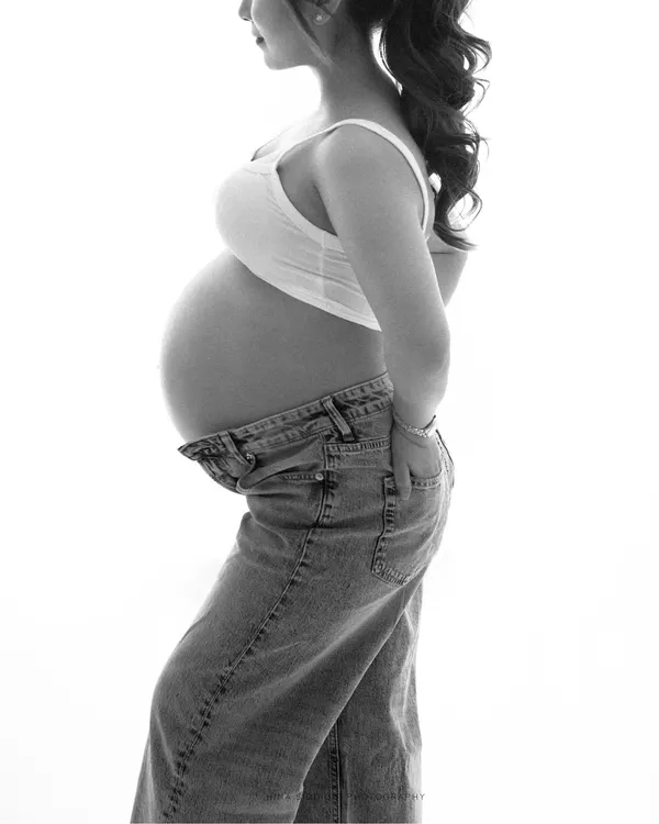 A simple and powerful black and white profile shot. This minimalist portrait beautifully highlights the silhouette of the baby bump, creating a classic and artistic image.