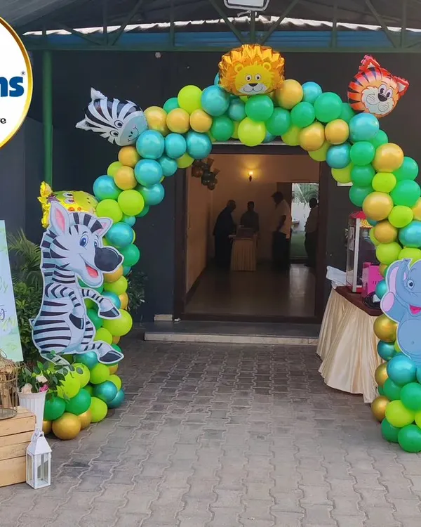 A grand balloon archway welcomes guests to a jungle-themed party. Character cutouts of a zebra and elephant stand at the entrance, setting the stage for the wild adventure inside.