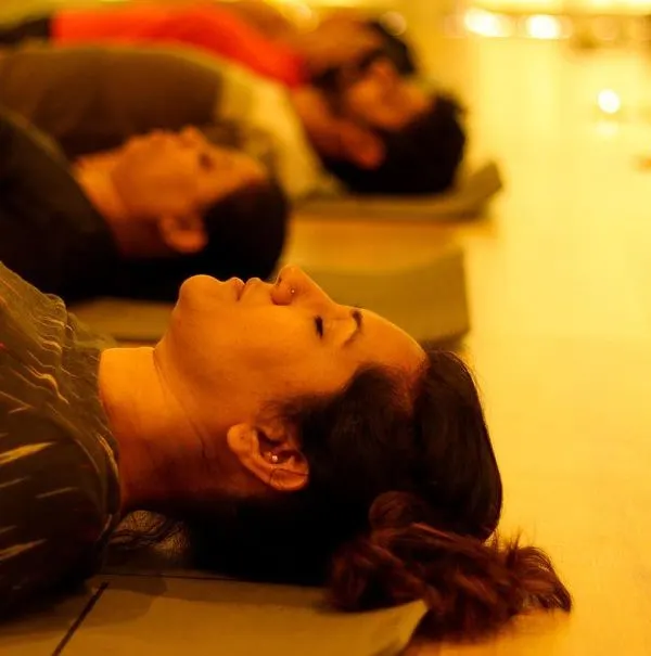 In the warm glow of candlelight, participants rest in Savasana during a sound bath. This state of deep relaxation allows the healing frequencies of the instruments to resonate fully through the body and mind.