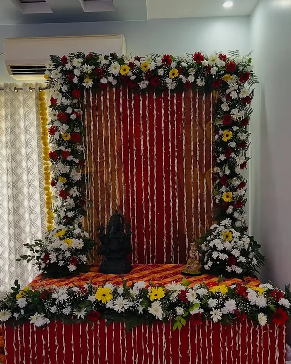 This is a beautiful floral setup for a home pooja or deity installation. I created a frame of fresh flowers around a red backdrop, with a decorated platform for the idol.