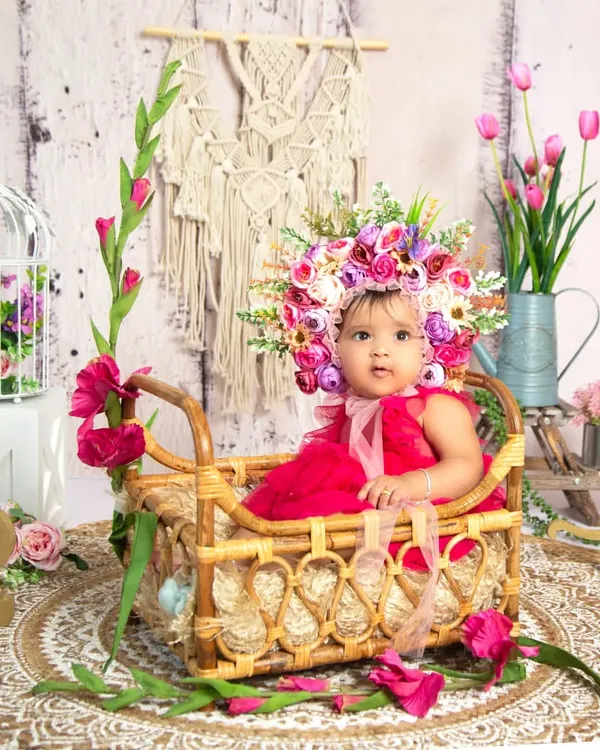 Celebrating six months with a beautiful half-birthday floral setup. The '1/2' sign, rustic basket, and a stunning flower bonnet make this a memorable sitter session.