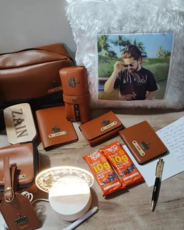 This personalized men's gift set includes a variety of tan leather accessories like a wallet, pouch, and luggage tag, all customized with a name and a crown charm. It also features a custom photo pillow.