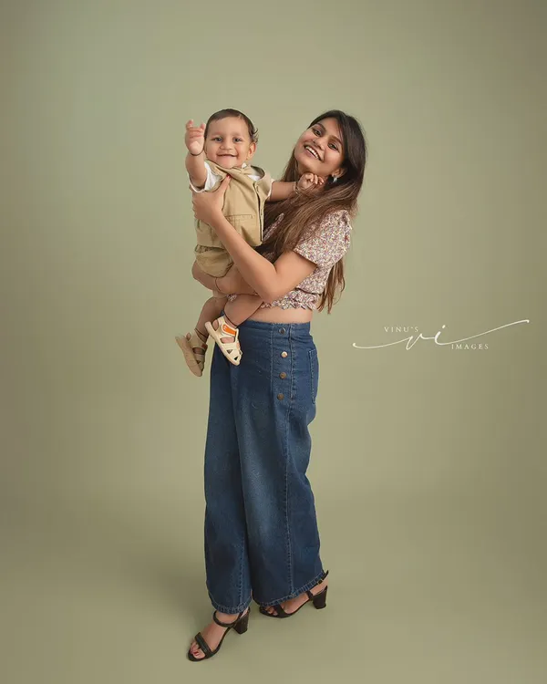 A mother's love and a baby's happy wave. This studio portrait captures a fun and loving moment between a mom and her son against a clean, simple backdrop.
