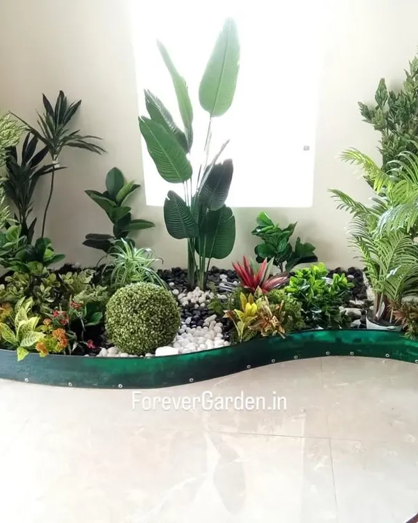 A beautiful, custom-designed indoor garden bed filled with a variety of artificial plants, including ferns, palms, and tropical foliage, creating a stunning focal point.