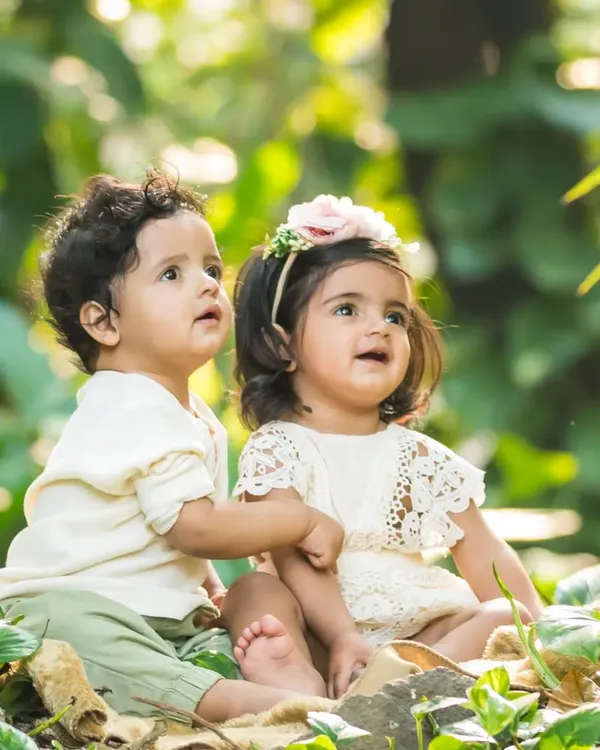 Two little explorers. These adorable twins, a boy and a girl, look up in wonder during their outdoor photoshoot, their bond clear to see.