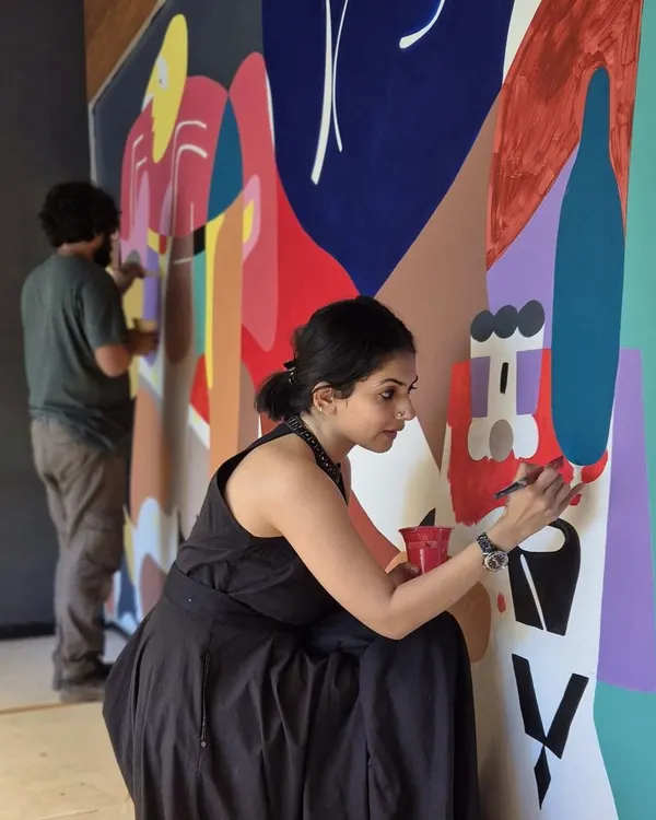 The artist at work, adding details to a large, colorful Picasso-inspired mural. This is where the vision starts to take tangible form.