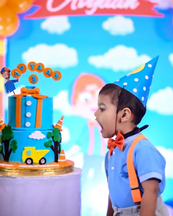 The moment of pure wonder right before the smash! This little one, dressed in a Blippi-inspired outfit, is amazed by his colorful birthday cake during his party.