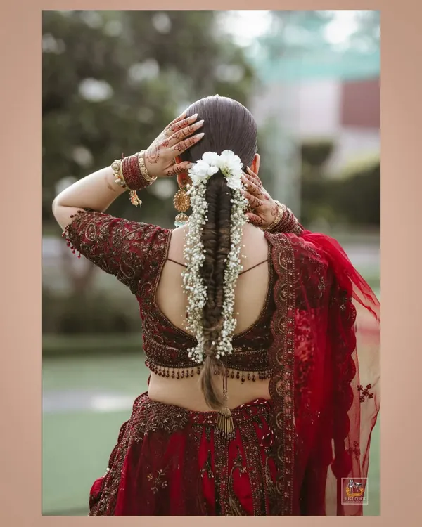 A beautiful shot focusing on the bride's intricate hairstyle with fresh flowers and her elegant blouse design.