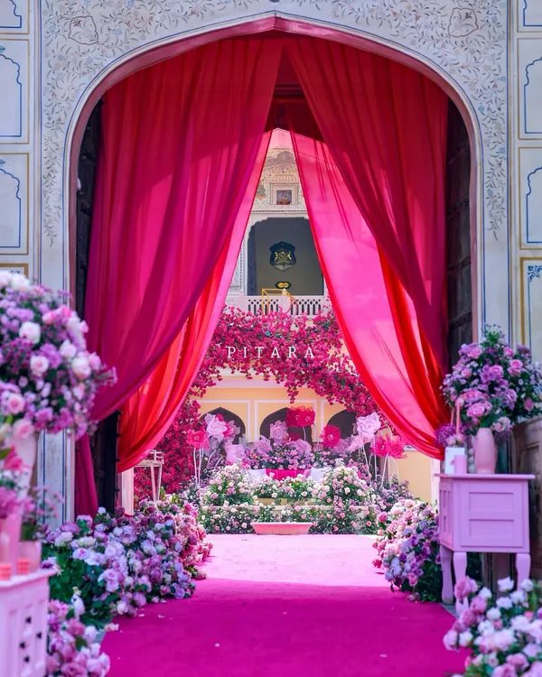 This is how we do royal entrances. A vibrant gulabi carpet and lush floral arrangements guide guests through majestic palace arches, framed by dramatic fuchsia drapes. It’s a welcome that promises the grandeur to come.