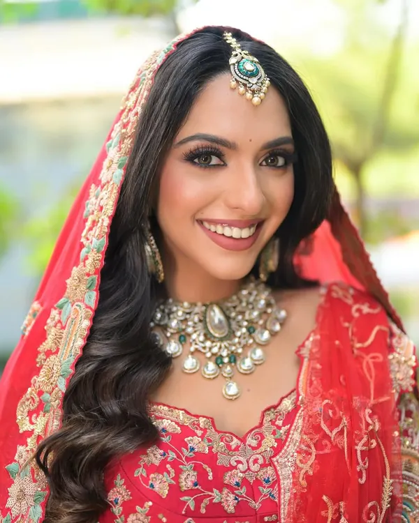 My signature bridal look is all about radiant confidence. This North Indian phera look features flawless skin, defined eyes, and a classic red lip, perfectly complementing the intricate red lehenga and polki jewellery.