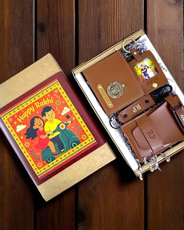 This Rakshabandhan hamper for a brother is packed with personalized vegan leather goods. It includes a wallet, passport cover, and keychains, all customized with names, initials, and charms, presented in a festive box.
