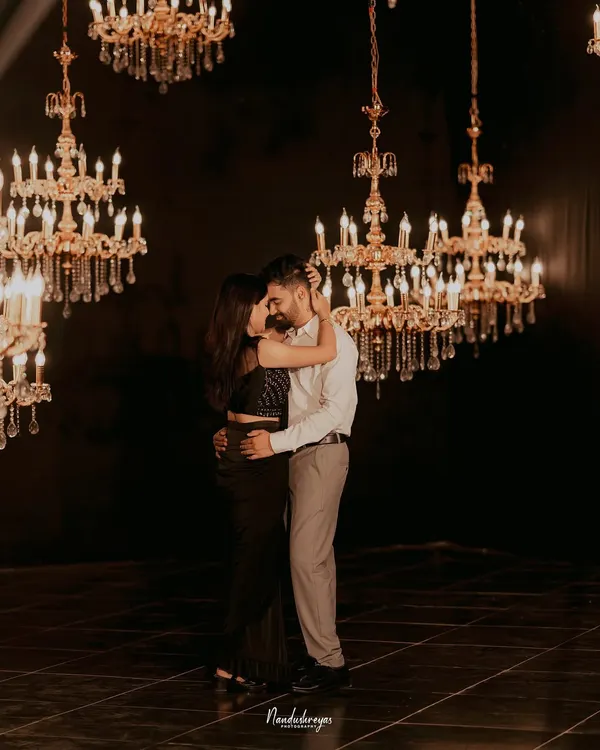 A couple shares an intimate dance, surrounded by a constellation of hanging crystal chandeliers. This shot exemplifies a glamorous and romantic indoor pre-wedding theme.