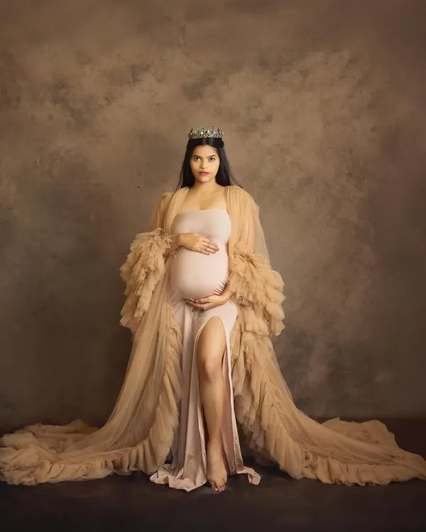A portrait of pure royalty. Wearing a crown and a beautiful nude gown, this mom-to-be looks absolutely regal, capturing the powerful essence of motherhood in a fine art studio setting.