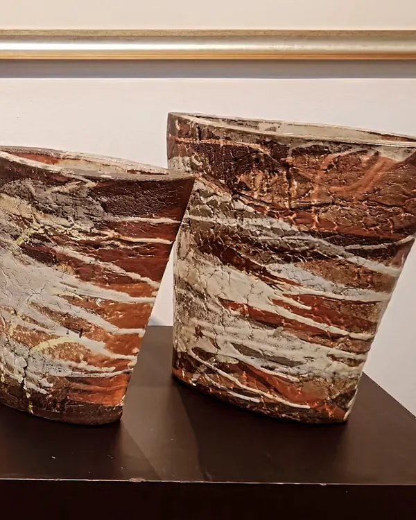 A pair of hand-built sculptural vases with a heavily textured, layered surface that mimics natural rock formations. These pieces are designed to be artistic focal points in any room.