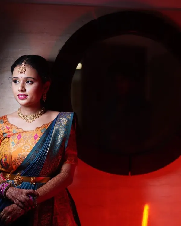 An artistic shot of Yoshitha, with dramatic red lighting highlighting her beautiful features and colorful lehenga.