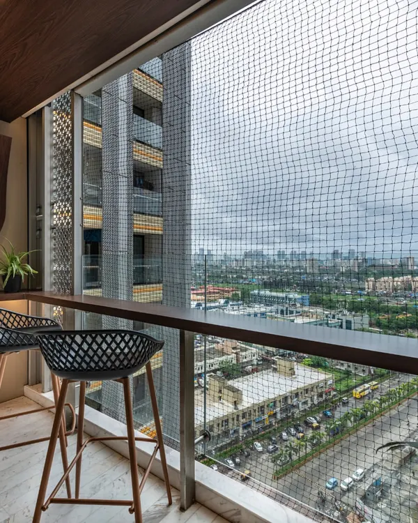 Tranquil elegance awaits on this balcony. With a bar-height counter and chic chairs, it's a serene retreat under open skies, offering a perfect spot to unwind and take in the city view.