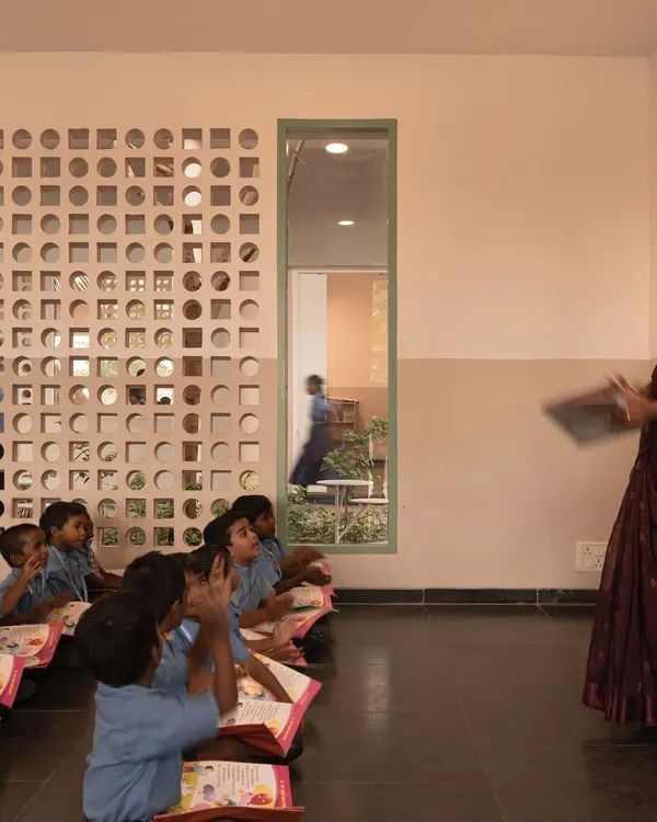 A classroom at the Talaricheruvu Rural School, where students sit on the floor in a traditional manner. The custom-designed jaali wall allows for cross-ventilation and fills the learning space with balanced, natural light.