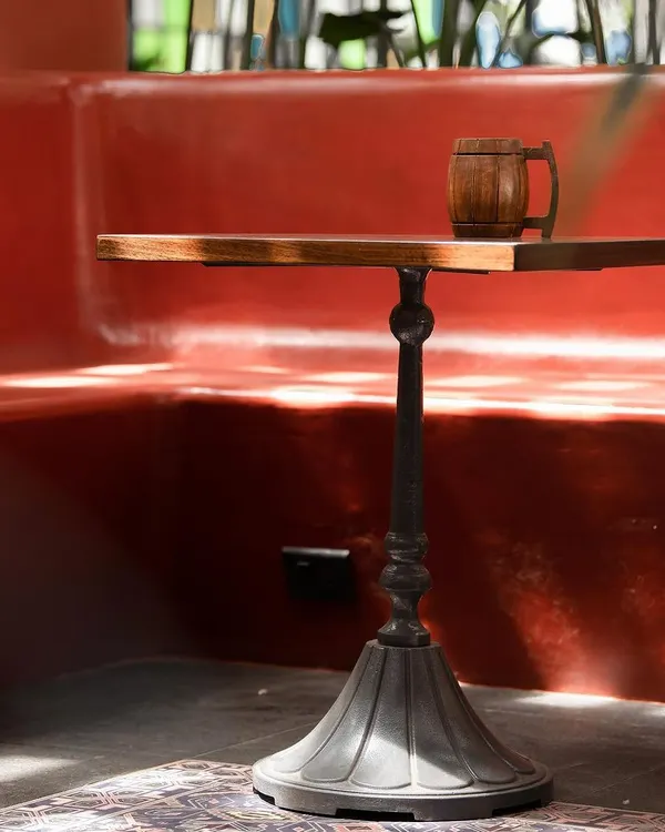 A custom-designed cast iron table base paired with a solid wood top, set against a red-oxide finished booth. We collaborate with skilled vendors like Loyora Spaces to create bespoke furniture that elevates the spaces we design.
