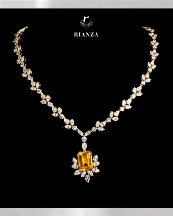This exquisite necklace features a magnificent 25-carat yellow sapphire as its centerpiece. The gemstone is beautifully complemented by a delicate setting of marquise and round diamonds, designed to make the wearer shine.